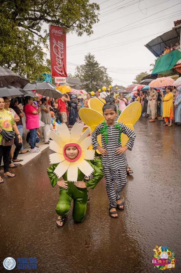 Two children in flower and bee fancy dress leading the parade in the rain