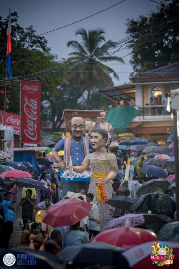Giant puppets towering over a sea of umbrellas